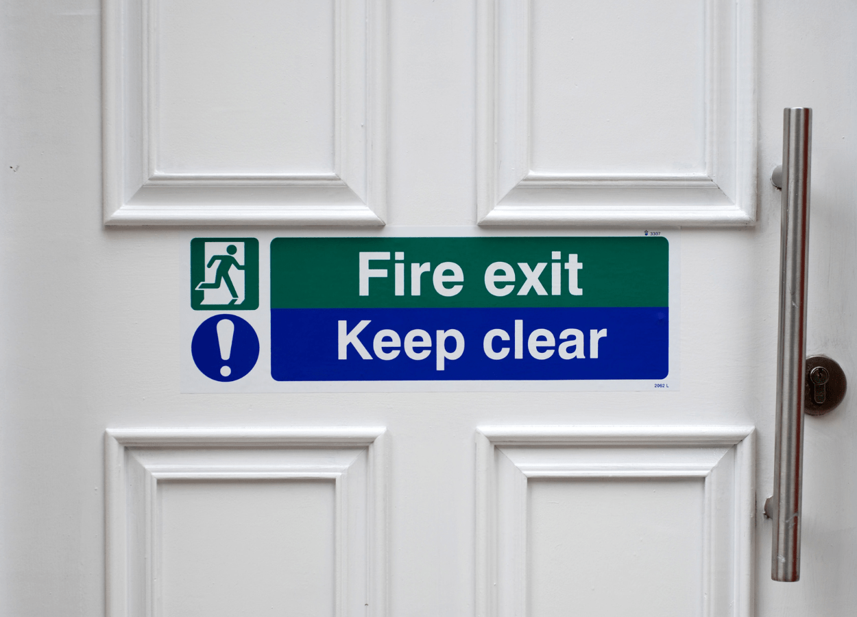 Fire-resistant door marked with fire exit and keep clear signs which is an example of what is classified as passive fire protection rather than active fire protection. 